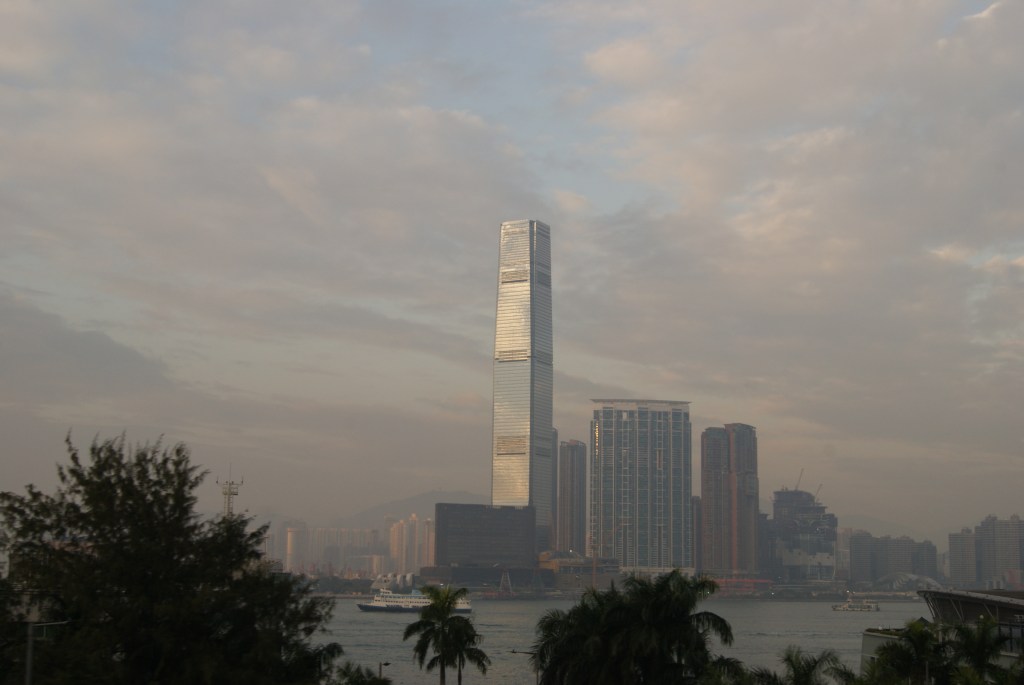 A city skyline at dusk framed with palm trees.